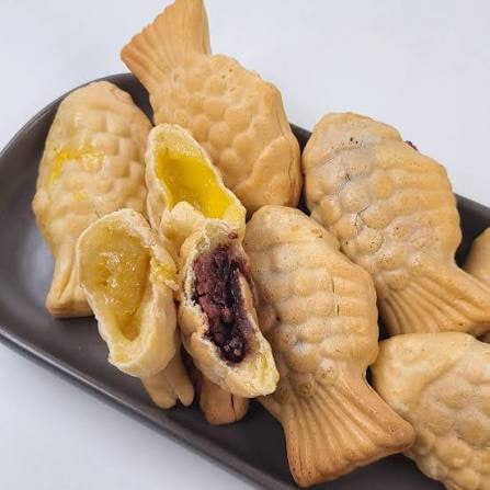 Bungeoppang fish-shaped pastries, one broken open to show red bean paste and another showing custard cream